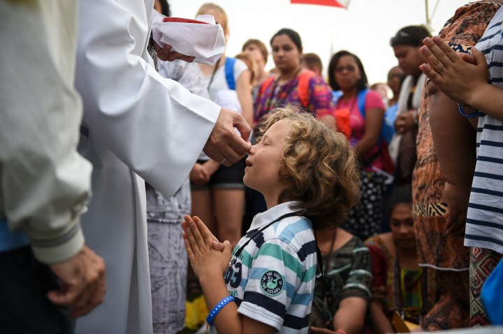 Catholic priest giving a little boy a Holy Communion