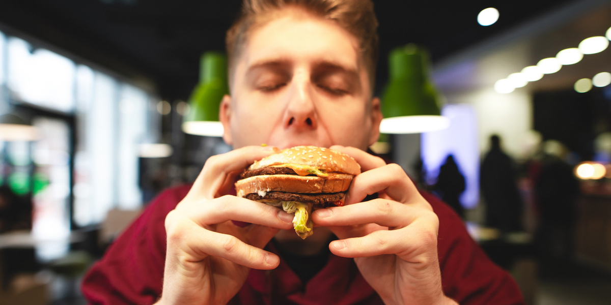 web3-young-man-eats-a-delicious-large-burger-with-his-eyes-closed-and-delights.-close-up-portrait-of-a-funny-man-biting-a-burger.-harmful-delicious-food-at-the-fast-food-restaurant-shutt.jpg