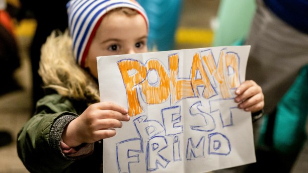 Chłopiec pokazuje kartkę z napisem "Polacy najlepsi przyjaciele"