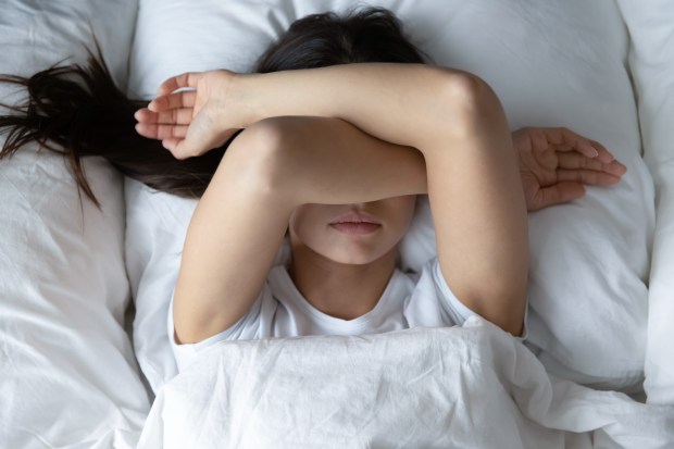 Chica tapándose la cara en la cama