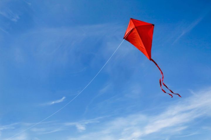 A red kite flying against a blue sky