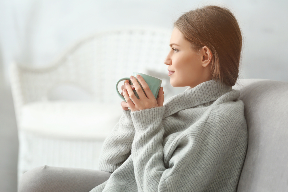 Beautiful young woman drinking tea while resting at home