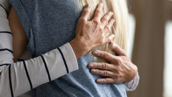 elderly woman hugs younger relative girl