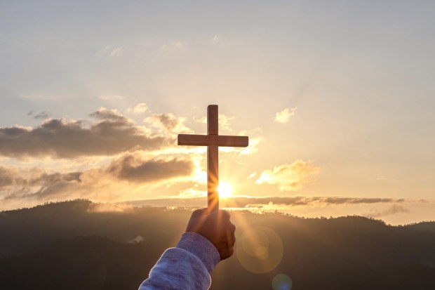 Christian Christianity Religion copy space background Human praying and holding christian cross for worshipping God at sunset background silhouette