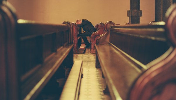 zasmucony mężczyzna siedzi w ławce w pustym kościele