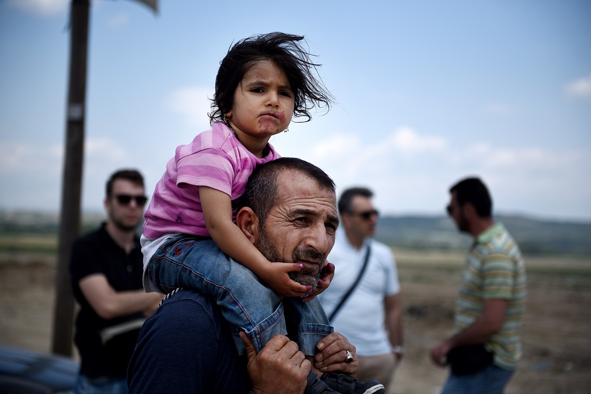 A Syrian man carries his daughter, as refugees abandon the makeshift camp of Idomeni in northern Greece