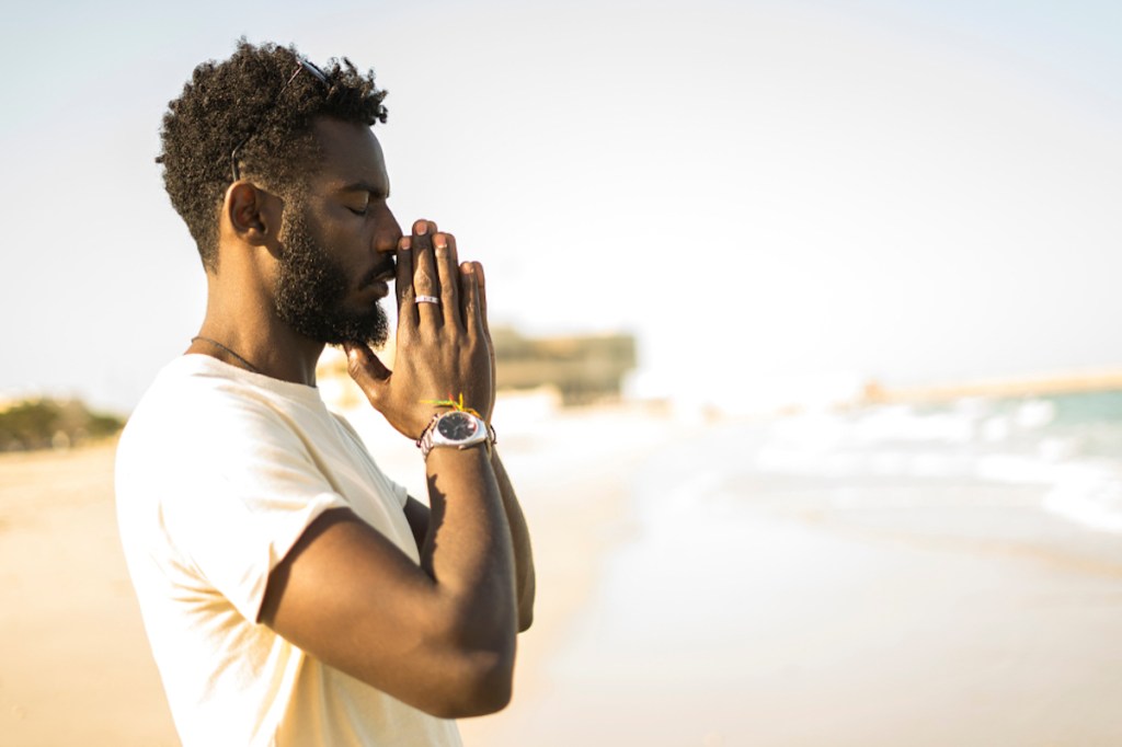 Homem rezando na praia