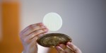 Ksiądz podnosi do góry Eucharystię