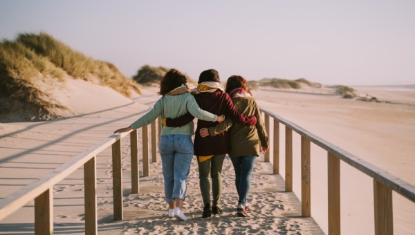 Three friends hugging each other while walking