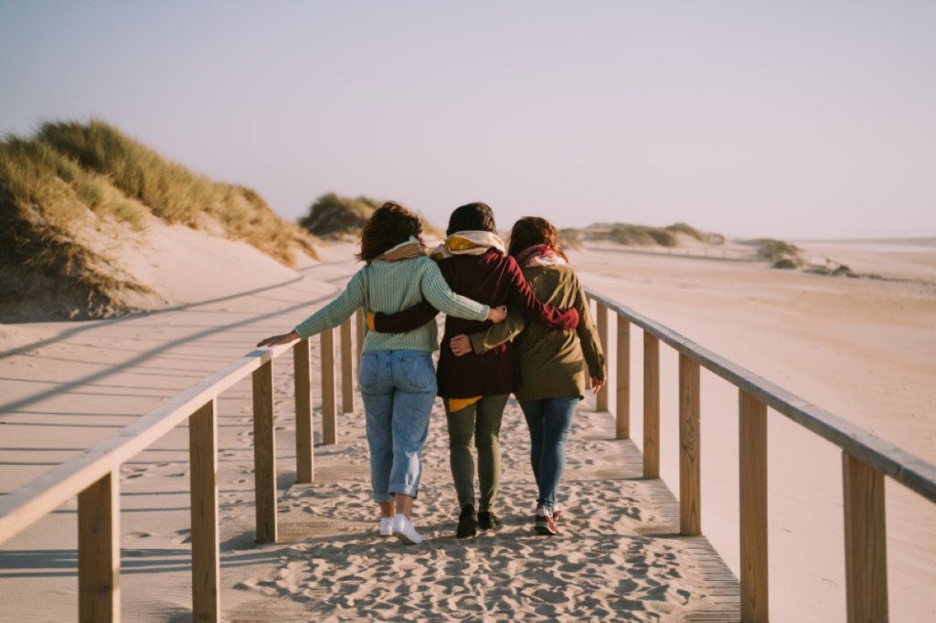 Three friends hugging each other while walking