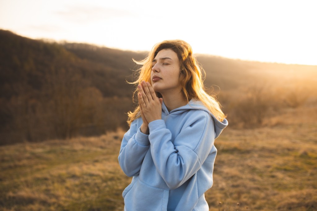 kobieta modli się na otwartej przestrzeni o zachodzie słońca