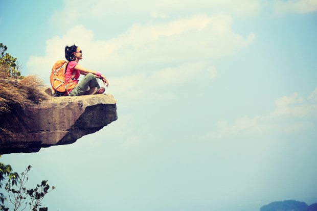 backpacker on rocky cliff looking out at sky