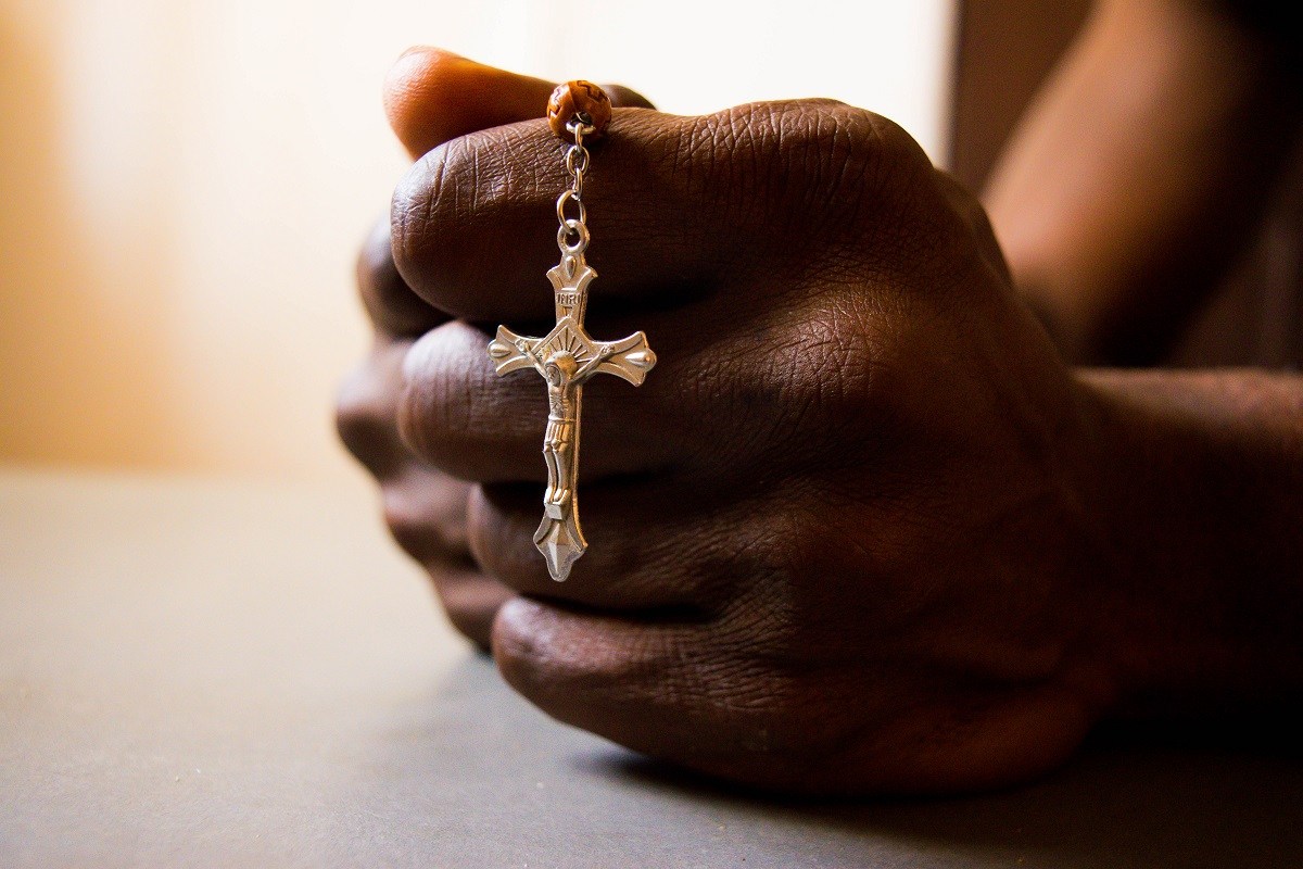 Nigerian man prays, hands, rosary