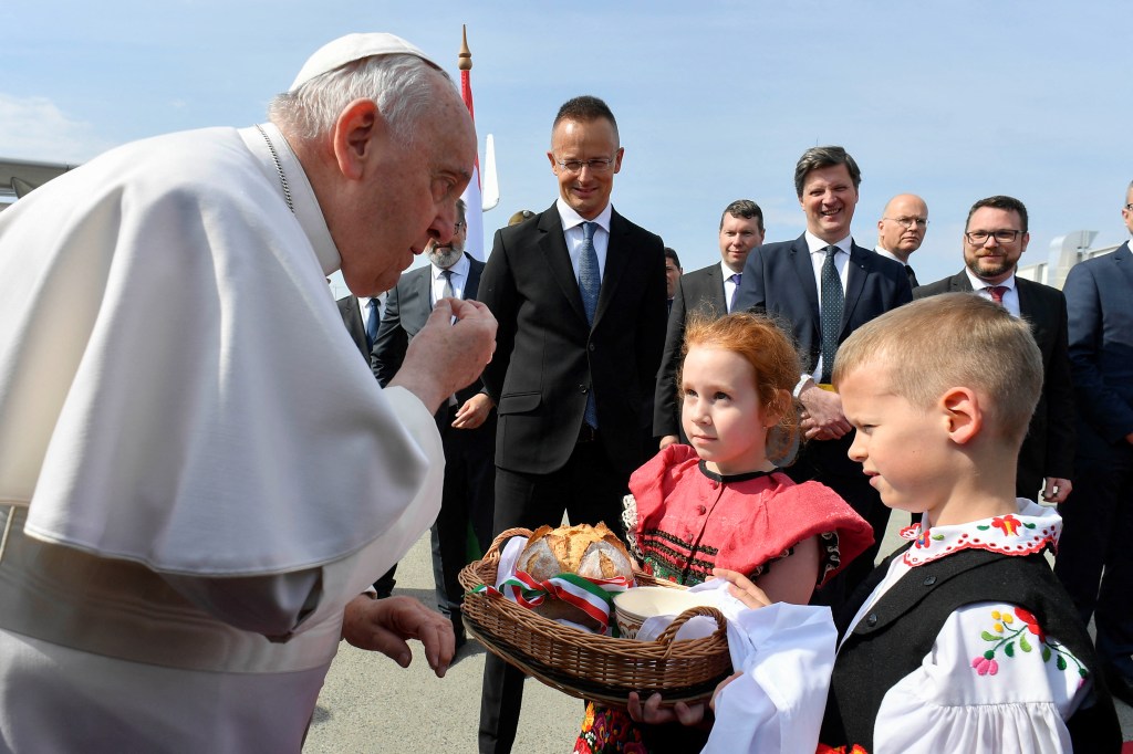 Papa Francisco (L) recibe pan y sal de niños vestidos con vestidos tradicionales húngaros a su llegada al aeropuerto Liszt Ferenc en Budapest el 28 de abril de 2023.