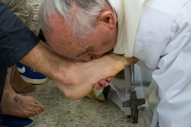 Pope Francis kissing the feet of a young offender after washing them during a mass at the church of the Casal del Marmo youth prison