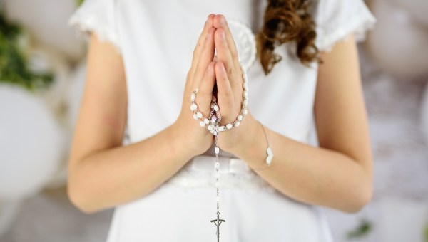 Hands of the First Communion girl folded in prayer