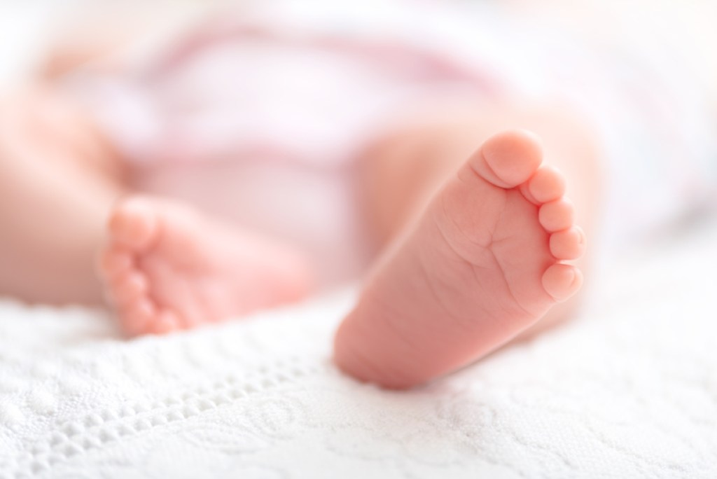 Newborn baby on a white blanket - tiny baby feet closeup