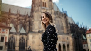 Uśmiechnięta młoda dziewczyna stoi przed katedrą w czeskiej Pradze