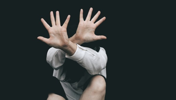 Kobieta zasłania się wyciągniętymi rękami