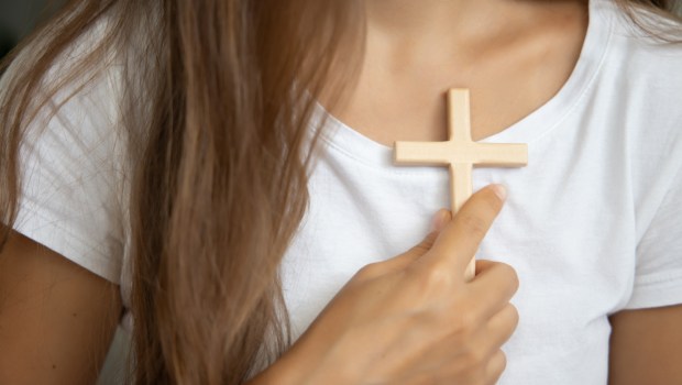 Kobieta trzyma krzyż przy swoim sercu