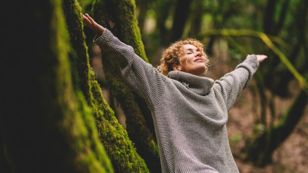 Una mujer feliz que disfruta del bosque verde y hermoso de la naturaleza