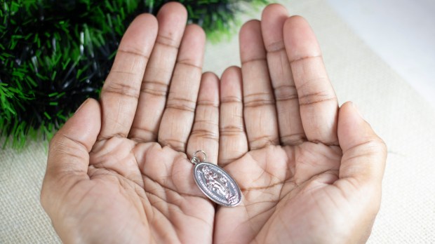 Girl-Hands-Holding-Miraculous-Medal-and-Praying-to-Our-Lady-Holy-Mary-Mother-of-God-shutterstock_1574