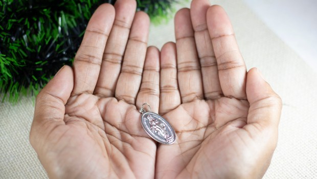 Girl-Hands-Holding-Miraculous-Medal-and-Praying-to-Our-Lady-Holy-Mary-Mother-of-God-shutterstock_1574