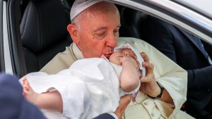 Pope Francis kisses a baby on his way to the Belem district's cultural centre in Lisbon, during his five-day visit to attend the World Youth Day