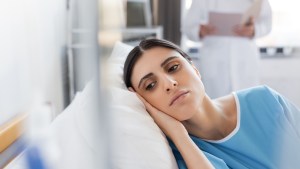 Paciente insatisfecho tumbado en la cama cerca de un médico borroso en la sala del hospital shutterstock_2247559525