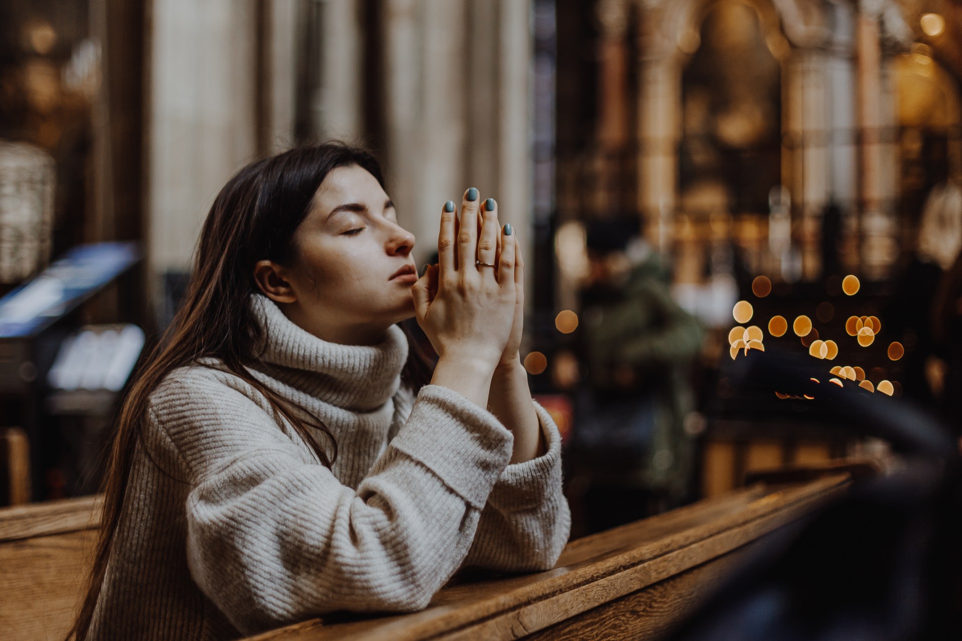 una-mujer-rezando-de-rodillas-en-un-antiguo-templo-catolico-a-Dios.-shutterstock_1719161167