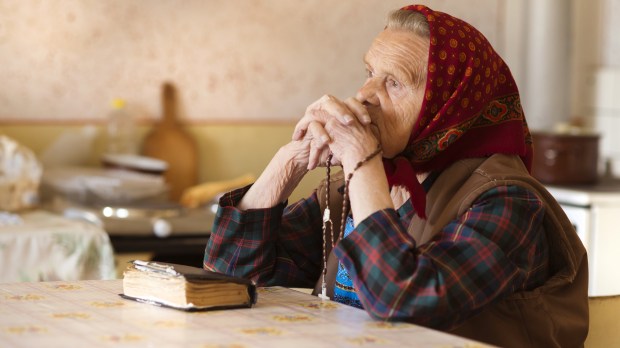 Very-old-woman-wearing-head-scarf-is-praying-in-her-country-style-kitchen-shutterstock