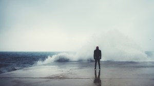 MAN IN FRONT OF GIANT WAVE