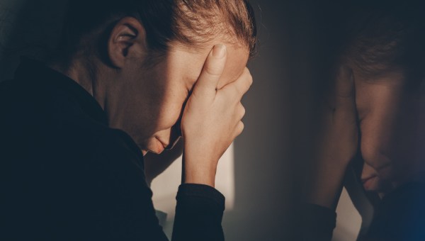 Pogrążona w smutku i żałobie kobieta skrywa twarz w dłoniach