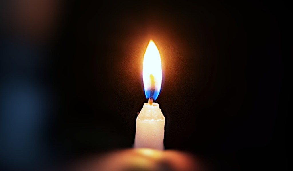 Candle held in hand in the darkness