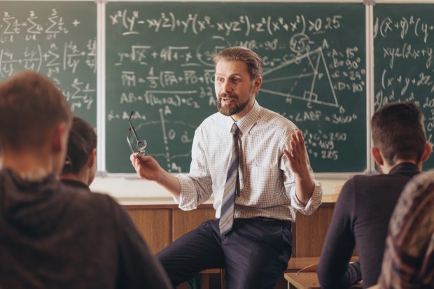 Nauczyciel matematyki z pasją wyjaśnia wzory swoim uczniom