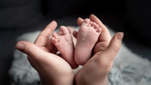 Hands hold baby feet