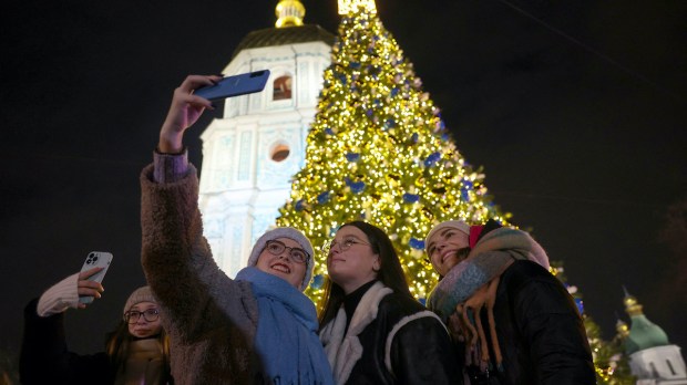 People taking selfie in front of Kyiv Ukraine Christmas tree