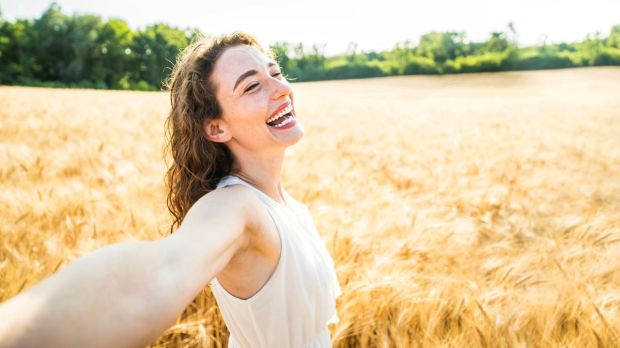Happy-woman-with-arms-outstretched-enjoying-freedom-in-a-wheat-field-shutterstock_2328881253