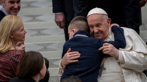 A kid hugs Pope Francis at the end of his weekly general audience