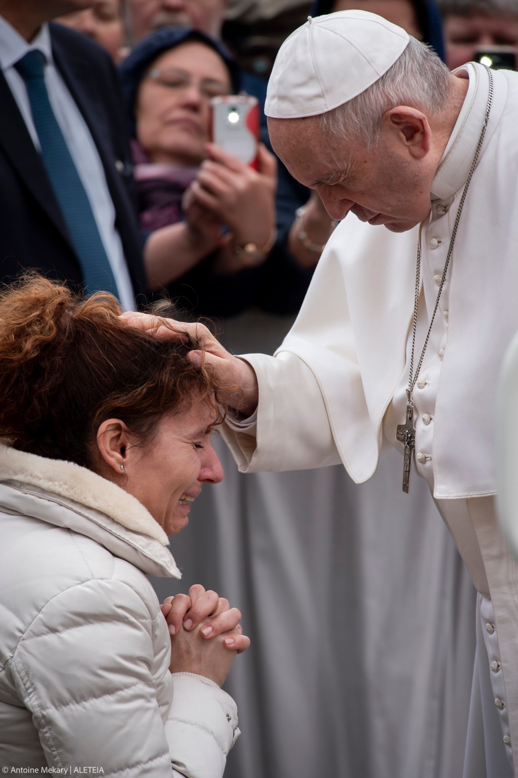 Pope Francis blesses a woman kneeling before him at the end of the weekly general audience