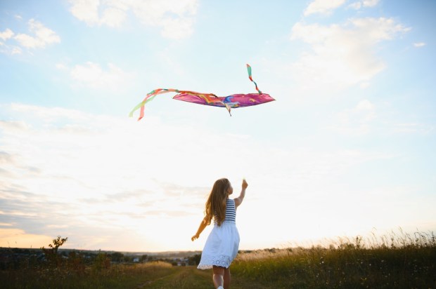 one happy little girl running on field with kite
