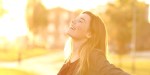 Back light portrait of a happy single teen girl breathing fresh air at sunset in a park