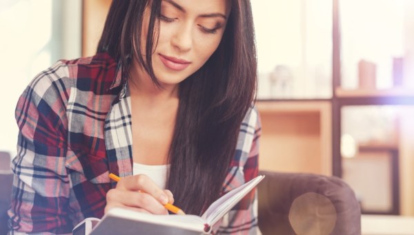 Woman with dark hair writing down a note