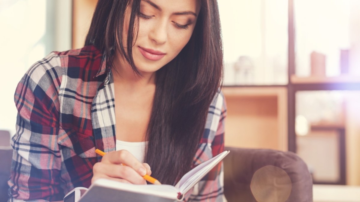 Woman with dark hair writing down a note