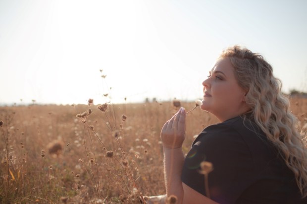 Portrait of beutiful plus size woman walks outdoor against the field and sunloght
