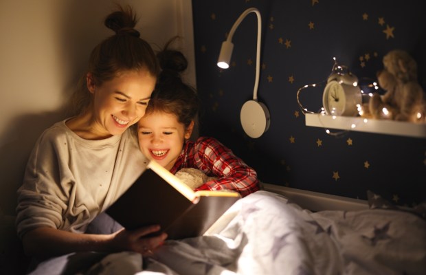 woman and girl smiling and reading fairytale