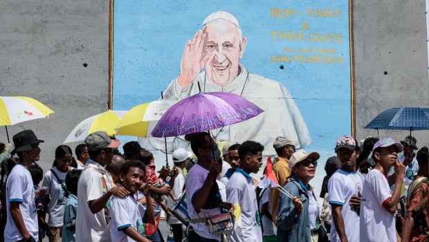 Catholic faithful walk in front of a graffiti of Pope Francis before a mass, which is expected to attract more than half of the country's 1.3 million people, in Dili on September 10, 2024.