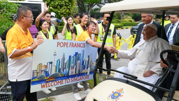 Pope Francis (2nd R) greets Catholic faithful welcoming him with a banner after his arrival in Singapore. Pope Francis touched down in Singapore on September 11, the last stop of a four-nation Asia-Pacific trip