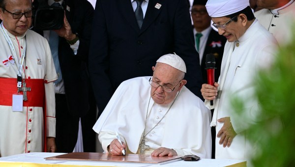 Grand Imam of Istiqlal Mosque Nasaruddin Umar (R) watches as Pope Francis signs during an interreligious meeting with religious leaders at the Istiqlal Mosque in Jakarta on September 5, 2024.