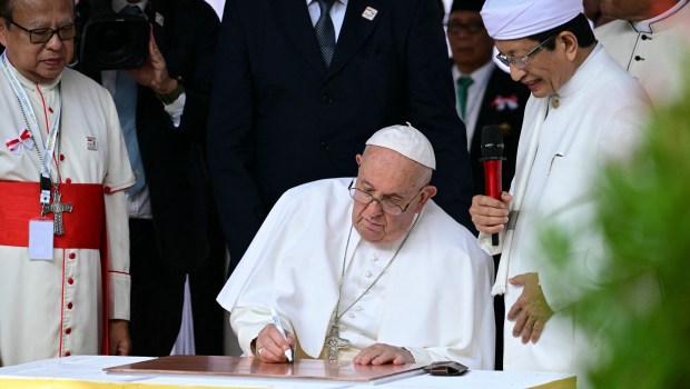 Grand Imam of Istiqlal Mosque Nasaruddin Umar (R) watches as Pope Francis signs during an interreligious meeting with religious leaders at the Istiqlal Mosque in Jakarta on September 5, 2024.